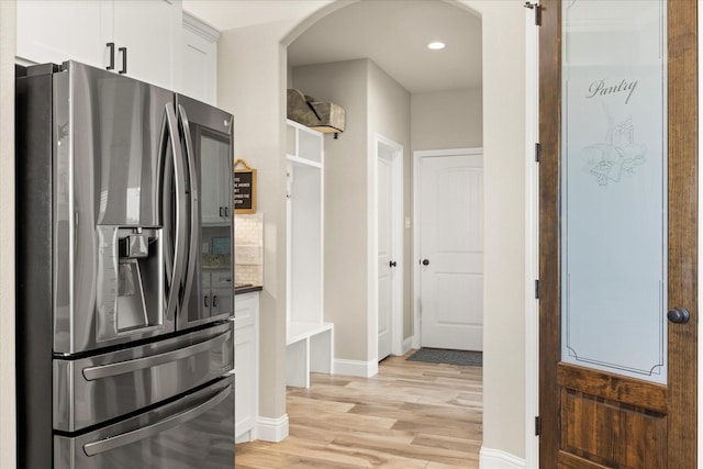 2141 Vanderbilt Dr, Weatherford, TX 76088 - kitchen with stainless steel refrigerator with ice dispenser, light wood finished floors, arched walkways, white cabinetry, and baseboards