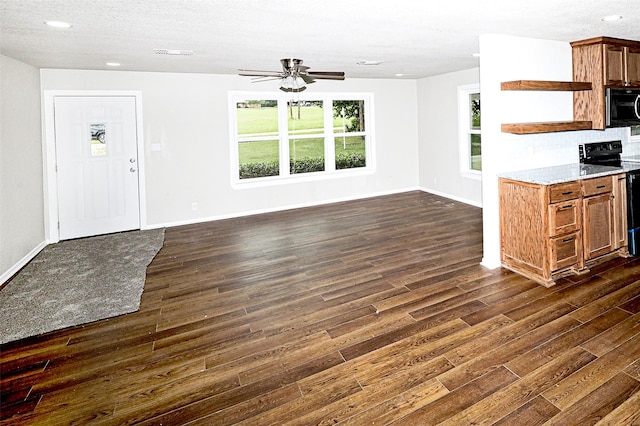 190 Trail Dr, Bowie, TX 76230 - kitchen with stainless steel microwave, electric range oven, open shelves, dark wood finished floors, and baseboards