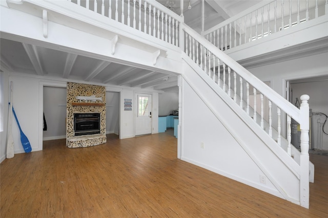 195 Cambridge Dr, Pottsboro, TX 75076 - unfurnished living room featuring wood finished floors, a tiled fireplace, stairway, beam ceiling, and baseboards