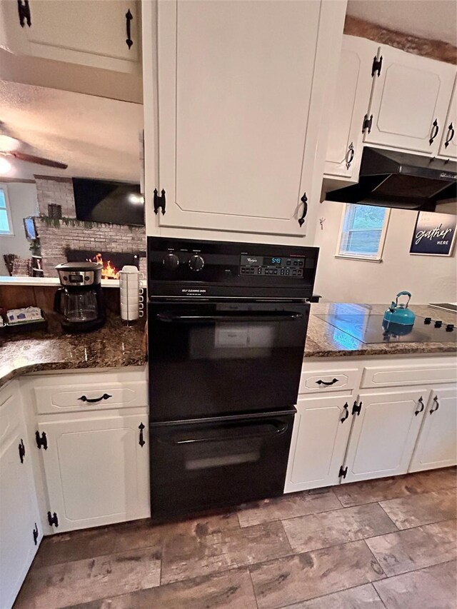 155 Saint Andrews Rd, Amarillo, TX 79118 - kitchen featuring white cabinetry, black appliances, under cabinet range hood, decorative backsplash, and dark stone counters