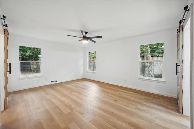 512 Shadowbrook Ln, Hurst, TX 76053 - unfurnished room with a barn door, light wood-style flooring, and healthy amount of natural light