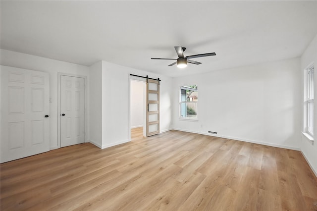 512 Shadowbrook Ln, Hurst, TX 76053 - unfurnished bedroom with a barn door, light wood-type flooring, baseboards, and ceiling fan