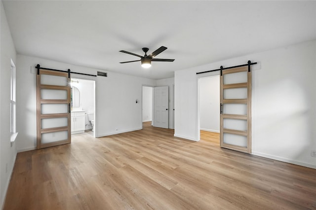 512 Shadowbrook Ln, Hurst, TX 76053 - unfurnished bedroom featuring a barn door, baseboards, and light wood finished floors
