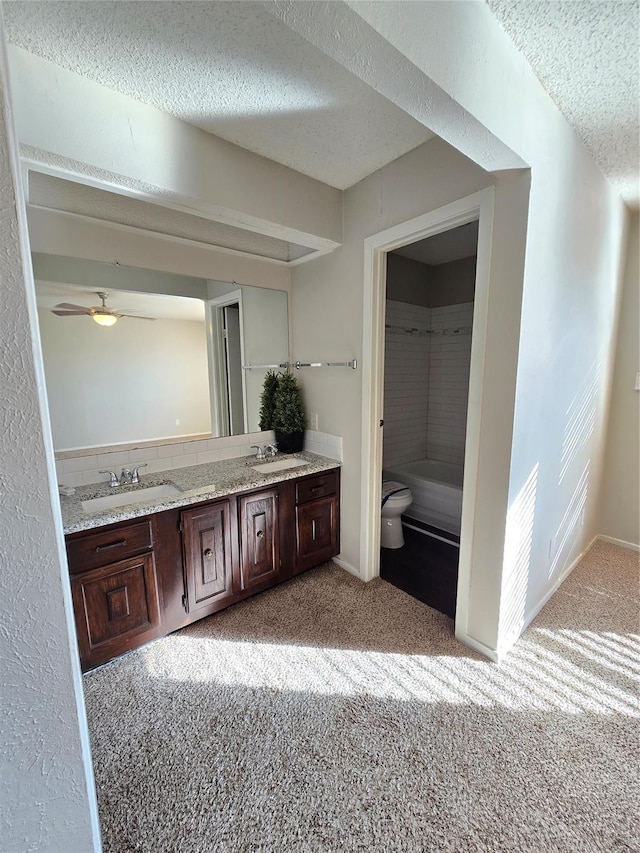 7008 Windhaven Rd, North Richland Hills, TX 76182 - bathroom with a textured ceiling, double vanity, toilet, a bath, and ceiling fan