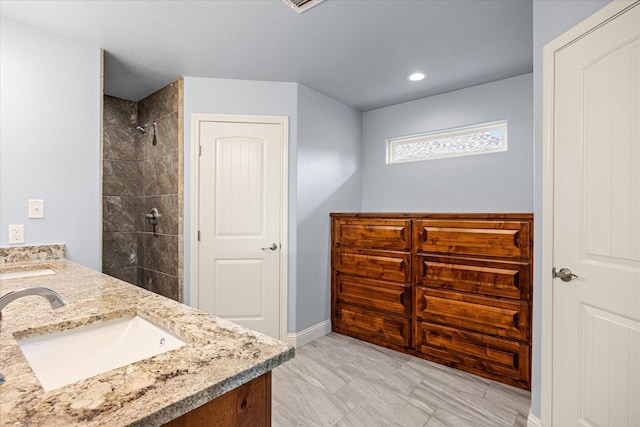 2615 San Gabriel Dr, Granbury, TX 76048 - bathroom featuring double vanity, tiled shower, baseboards, and recessed lighting