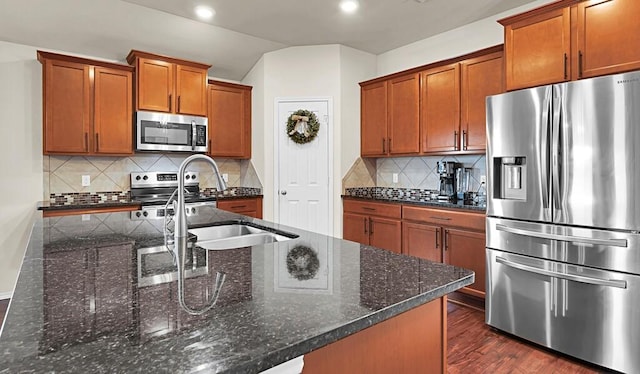 3200 Keathley Dr, Waco, TX 76655 - kitchen with appliances with stainless steel finishes, tasteful backsplash, a sink, brown cabinets, and dark stone counters