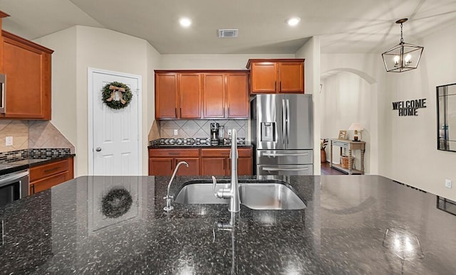 3200 Keathley Dr, Waco, TX 76655 - kitchen featuring appliances with stainless steel finishes, backsplash, a chandelier, brown cabinets, and dark stone counters