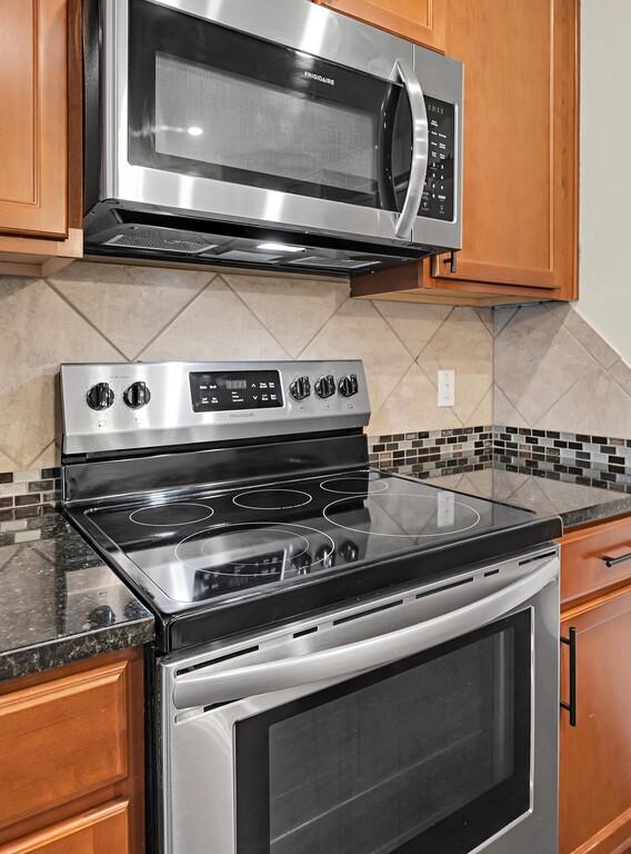 3200 Keathley Dr, Waco, TX 76655 - kitchen featuring appliances with stainless steel finishes, tasteful backsplash, brown cabinets, and dark stone countertops