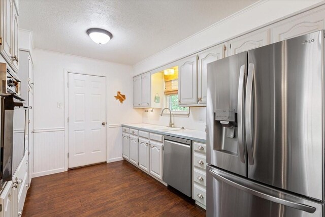 7844 Fairway Rd, Woodway, TX 76712 - kitchen featuring appliances with stainless steel finishes, a sink, a textured ceiling, dark wood-style flooring, and light countertops