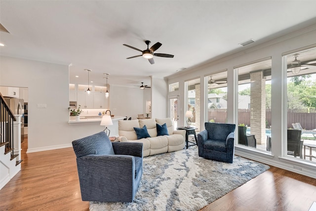 2403 Legend Dr, Heath, TX 75032 - living area featuring a ceiling fan, stairway, crown molding, light wood-style flooring, and baseboards