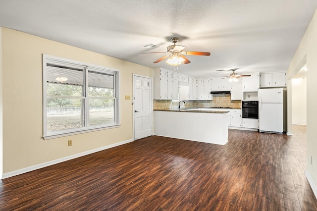 281 Lakeside Dr, China Spring, TX 76633 - kitchen featuring white appliances, dark countertops, a peninsula, decorative backsplash, and under cabinet range hood