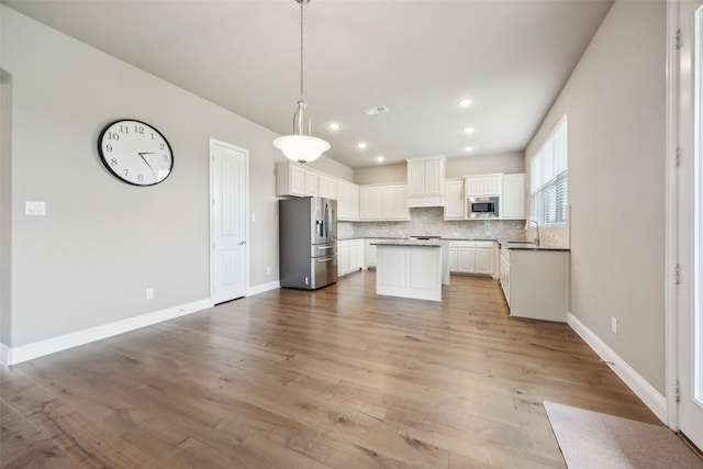 2608 Morning Mist Ln, Nevada, TX 75173 - kitchen featuring appliances with stainless steel finishes, a sink, decorative backsplash, white cabinets, and a kitchen island