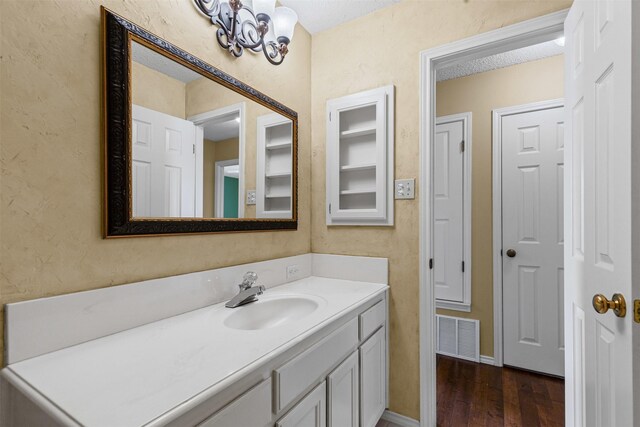 1505 Hyde Park Blvd, Cleburne, TX 76033 - bathroom featuring vanity, wood finished floors, a textured wall, and a chandelier
