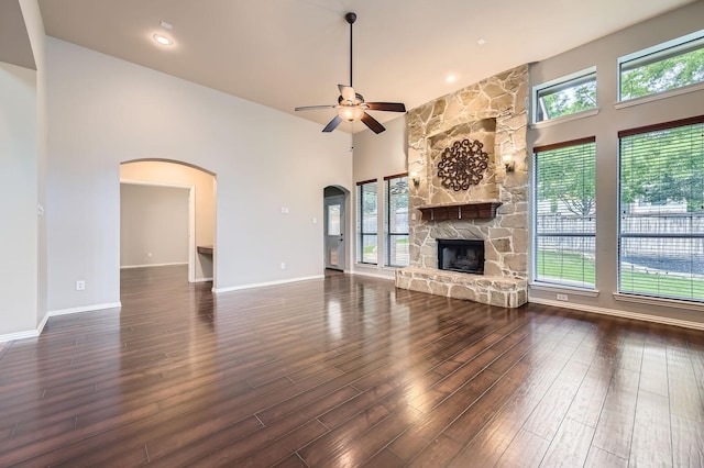 9028 Wiggins Dr, Fort Worth, TX 76244 - unfurnished living room with arched walkways, a ceiling fan, wood finished floors, a high ceiling, and a stone fireplace