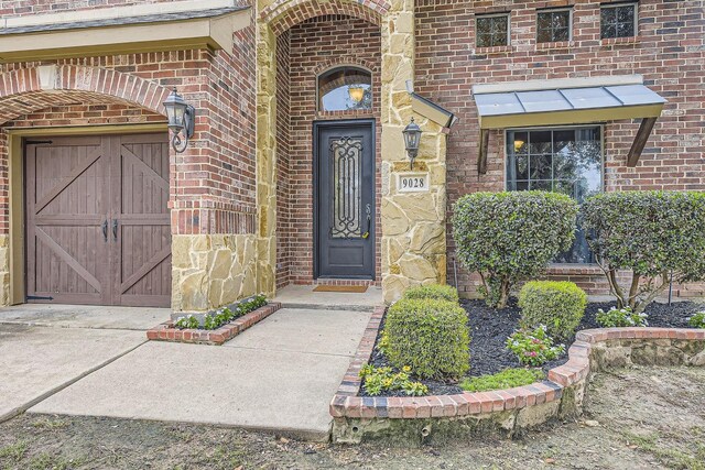 9028 Wiggins Dr, Fort Worth, TX 76244 - property entrance featuring brick siding, a garage, and driveway