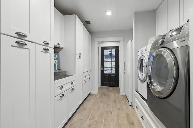 4009 Seminole Trl, Granbury, TX 76048 - laundry room featuring washer and dryer, light wood finished floors, and cabinet space