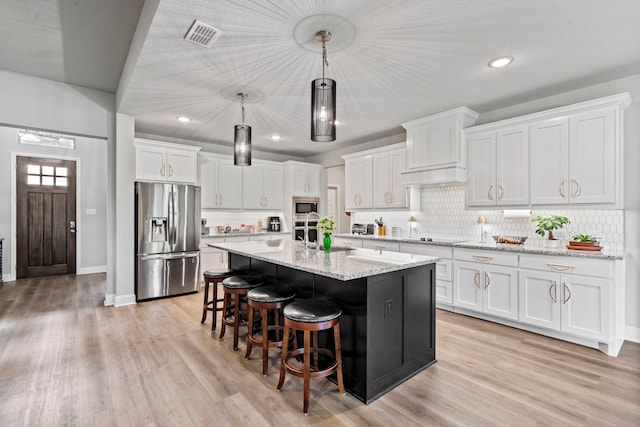105 Aslan Rd, Poolville, TX 76487 - kitchen featuring appliances with stainless steel finishes, white cabinets, a kitchen breakfast bar, tasteful backsplash, and a center island with sink