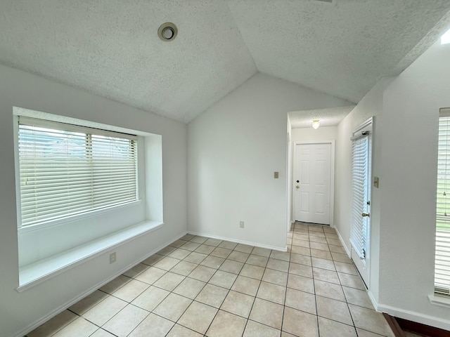 617 Desoto Dr, Desoto, TX 75115 - unfurnished room with a textured ceiling, vaulted ceiling, light tile patterned floors, and baseboards