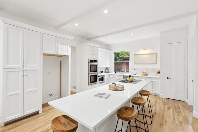 5920 Loch Lomond Dr, Plano, TX 75093 - kitchen with light wood-type flooring, a breakfast bar area, white cabinetry, beam ceiling, and stainless steel appliances