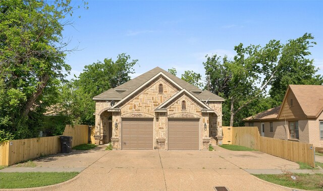 3116 Frazier Ave, Fort Worth, TX 76110 - french country style house featuring driveway, stone siding, an attached garage, and brick siding