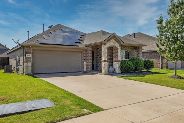 404 Madrone Ln, Princeton, TX 75407 - view of front of property with brick siding, an attached garage, a front yard, a shingled roof, and roof mounted solar panels