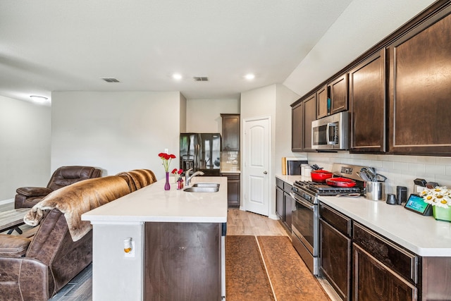 404 Madrone Ln, Princeton, TX 75407 - kitchen featuring appliances with stainless steel finishes, open floor plan, a sink, light wood finished floors, and dark brown cabinets