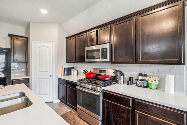 404 Madrone Ln, Princeton, TX 75407 - kitchen featuring appliances with stainless steel finishes, light countertops, dark brown cabinets, backsplash, and light wood finished floors