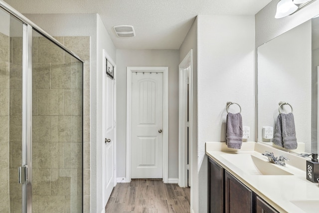404 Madrone Ln, Princeton, TX 75407 - full bathroom with a shower stall, double vanity, wood finished floors, and a textured ceiling