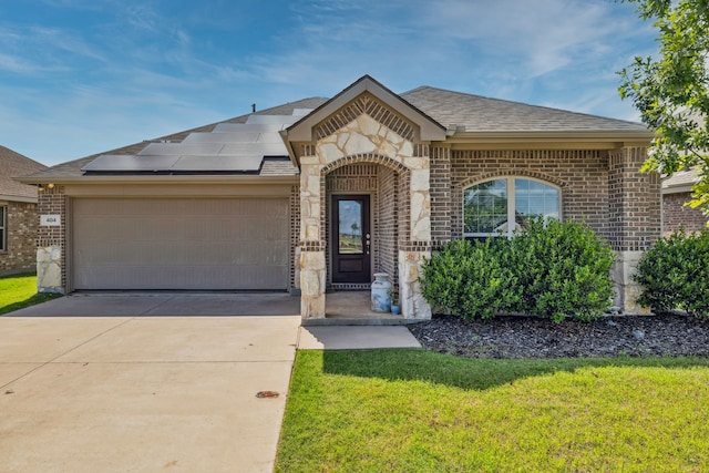 404 Madrone Ln, Princeton, TX 75407 - view of front of home featuring brick siding, an attached garage, roof mounted solar panels, a front lawn, and driveway