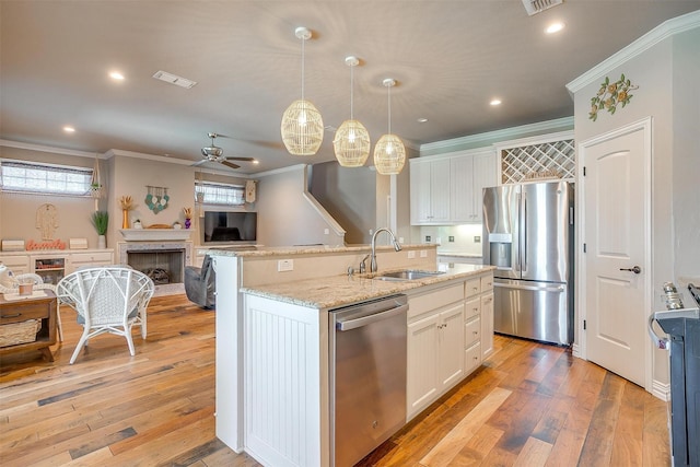 106 Camelot St, Glen Rose, TX 76043 - kitchen with stainless steel appliances, a fireplace, a ceiling fan, crown molding, and white cabinetry