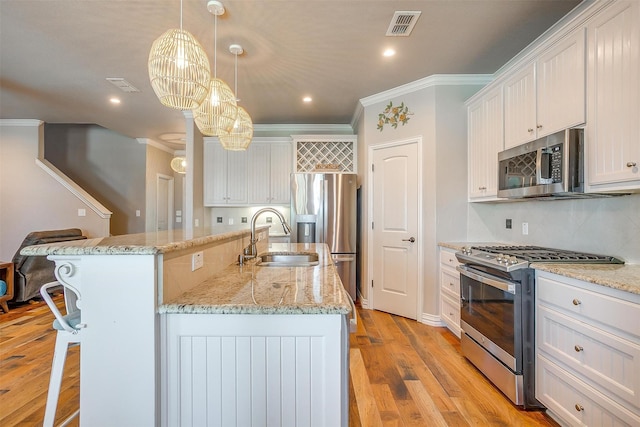 106 Camelot St, Glen Rose, TX 76043 - kitchen featuring appliances with stainless steel finishes, crown molding, a center island with sink, white cabinetry, and a kitchen bar