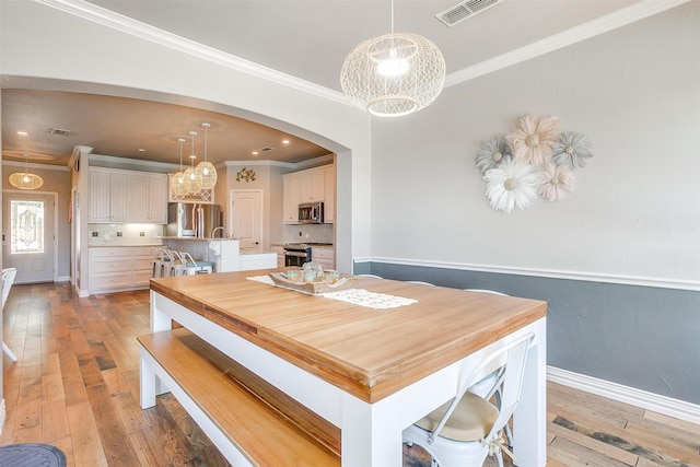 106 Camelot St, Glen Rose, TX 76043 - dining room with arched walkways, light wood-style floors, crown molding, and a chandelier