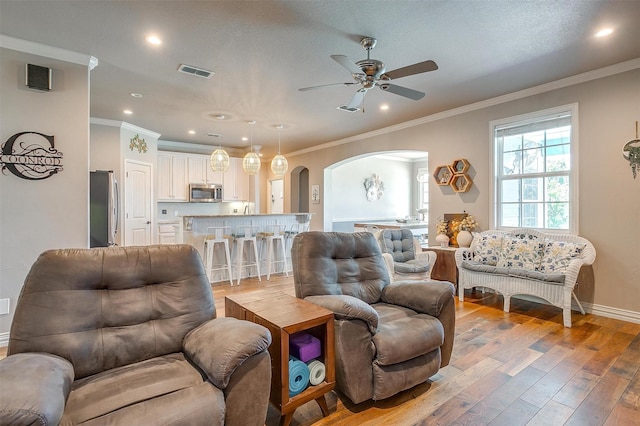 106 Camelot St, Glen Rose, TX 76043 - living room with arched walkways, light wood-style flooring, a ceiling fan, crown molding, and recessed lighting