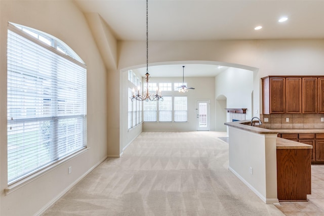 1728 Sandpiper Ln, Carrollton, TX 75007 - kitchen featuring arched walkways, brown cabinetry, a chandelier, decorative backsplash, and light colored carpet