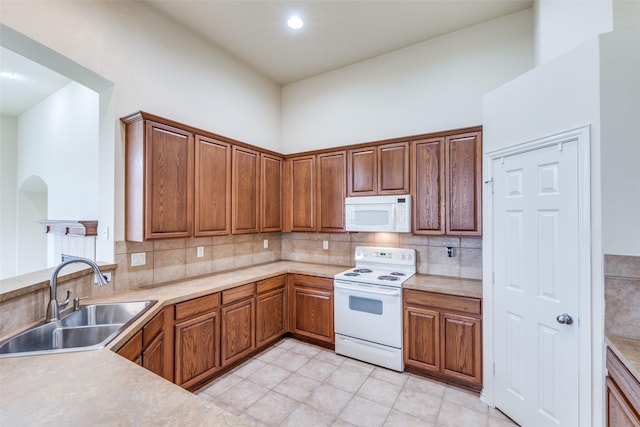 1728 Sandpiper Ln, Carrollton, TX 75007 - kitchen featuring white appliances, a sink, backsplash, light countertops, and brown cabinets