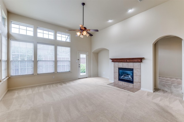 1728 Sandpiper Ln, Carrollton, TX 75007 - unfurnished living room featuring carpet, arched walkways, a ceiling fan, a tiled fireplace, and baseboards