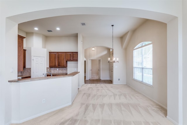 1728 Sandpiper Ln, Carrollton, TX 75007 - kitchen with arched walkways, brown cabinetry, backsplash, light carpet, and a chandelier