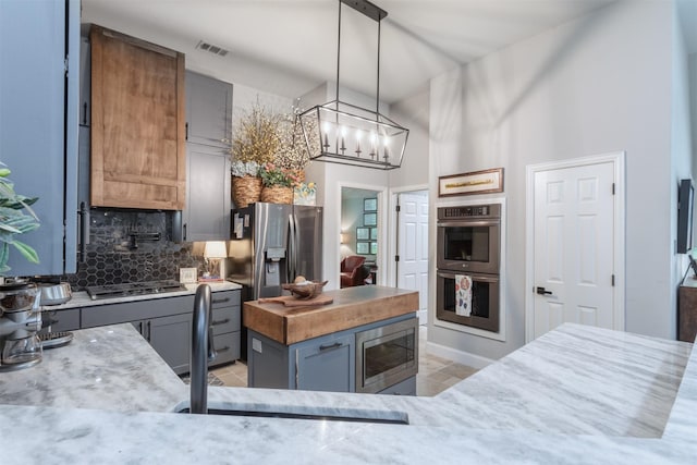 507 Clover Leaf Ln, Mckinney, TX 75072 - kitchen with appliances with stainless steel finishes, backsplash, light tile patterned flooring, gray cabinets, and pendant lighting