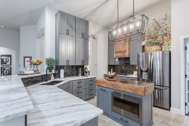507 Clover Leaf Ln, Mckinney, TX 75072 - kitchen featuring a sink, arched walkways, appliances with stainless steel finishes, butcher block counters, and gray cabinetry