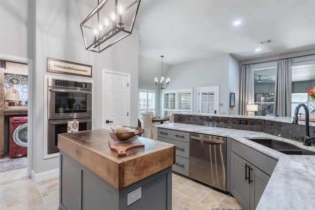 507 Clover Leaf Ln, Mckinney, TX 75072 - kitchen featuring appliances with stainless steel finishes, washer / dryer, a sink, gray cabinets, and a chandelier