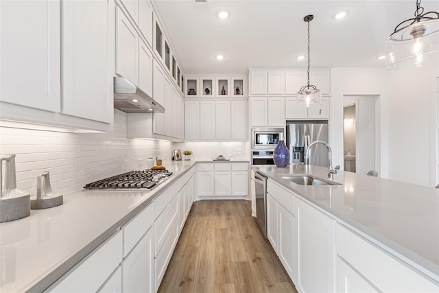 8120 Bromley Dr, Dallas, TX 75231 - kitchen with a sink, appliances with stainless steel finishes, ventilation hood, white cabinetry, and backsplash