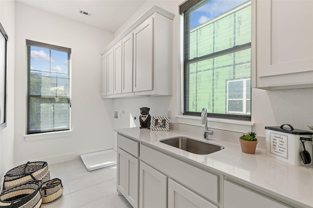 8120 Bromley Dr, Dallas, TX 75231 - kitchen featuring a sink, light countertops, light tile patterned floors, and white cabinetry