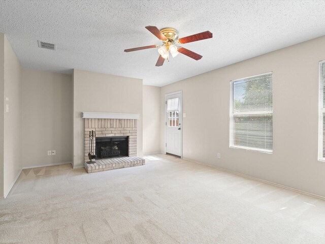 7605 Mosspoint Ct, Denton, TX 76210 - unfurnished living room with ceiling fan, carpet flooring, a brick fireplace, a textured ceiling, and baseboards