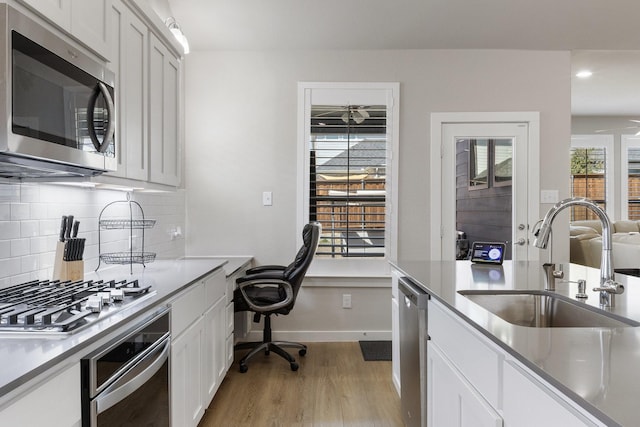 2012 Edgewater St, Celina, TX 75009 - kitchen with appliances with stainless steel finishes, a sink, light wood-style flooring, decorative backsplash, and white cabinetry