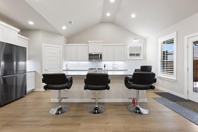 2012 Edgewater St, Celina, TX 75009 - kitchen featuring appliances with stainless steel finishes, light wood-type flooring, white cabinetry, a breakfast bar area, and recessed lighting