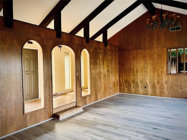 310 Lori Ln, Brownwood, TX 76801 - unfurnished room featuring wooden walls, beam ceiling, wood finished floors, a chandelier, and high vaulted ceiling