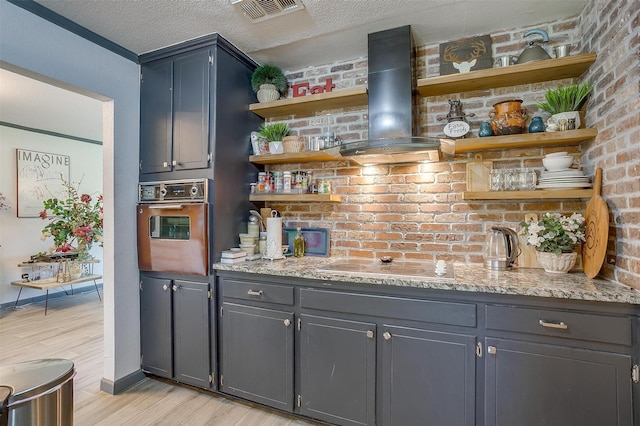 905 E Renfro St, Burleson, TX 76028 - indoor wet bar featuring wall oven, wall chimney range hood, light wood-type flooring, electric stovetop, and baseboards