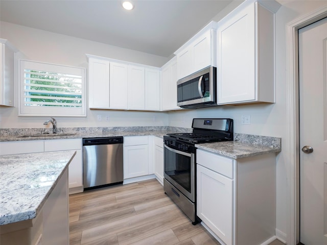 1218 Parker Dr, Princeton, TX 75407 - kitchen with stainless steel appliances, white cabinetry, light stone countertops, recessed lighting, and light wood-style floors