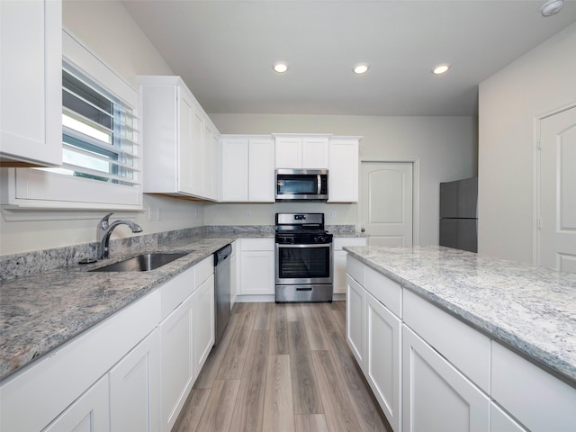 1218 Parker Dr, Princeton, TX 75407 - kitchen with appliances with stainless steel finishes, white cabinetry, light wood-style flooring, light stone counters, and recessed lighting