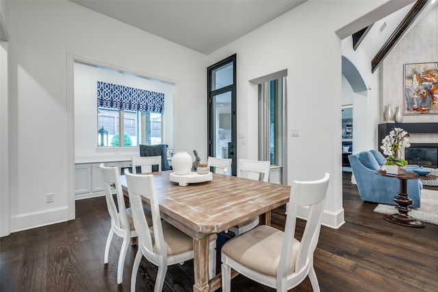2021 Longmont Ln, Prosper, TX 75078 - dining room with dark wood finished floors, arched walkways, a large fireplace, and baseboards